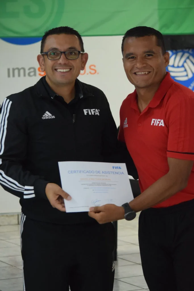 Árbitros salvadoreños - Juan Francisco Zumba (camisa roja) posa para una fotografía con un asistente del curso RAP para árbitros élite. 